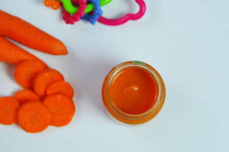 baby carrot mashed, food, puree with spoon in glass jar on white backgroundの写真素材