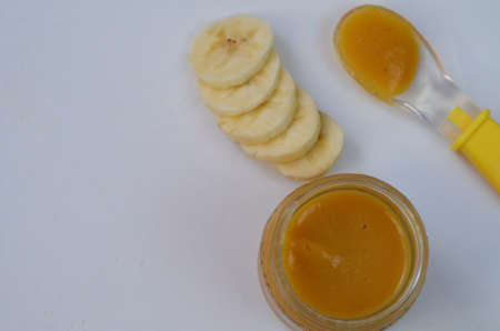 Baby food, banana mashed puree and bananas on a white backgroundの写真素材