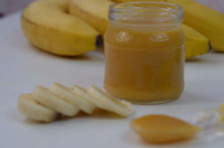 Baby food, banana mashed puree and bananas on a white backgroundの写真素材
