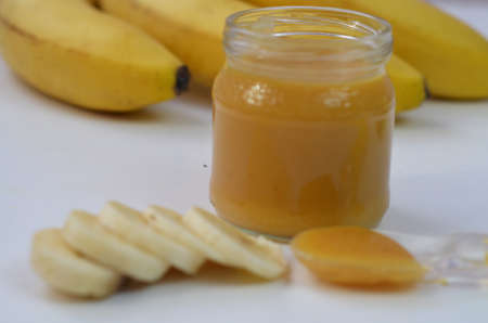 Baby food, banana mashed puree and bananas on a white backgroundの写真素材