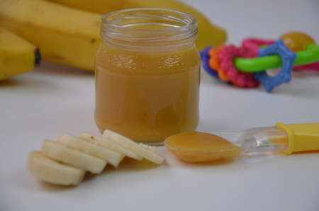 Baby food, banana mashed puree and bananas on a white backgroundの写真素材