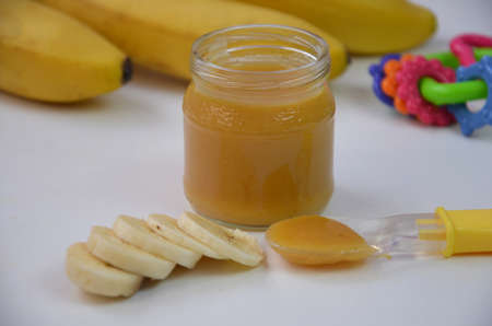 Baby food, banana mashed puree and bananas on a white backgroundの写真素材