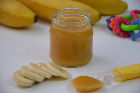 Baby food, banana mashed puree and bananas on a white backgroundの写真素材