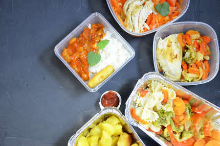 Healthy food and diet concept, restaurant dish delivery. Take away of fitness meal. Weight loss nutrition in foil boxes. eats and works computer. Food storage in containers. Freelance. Work at homeの写真素材