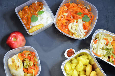 Healthy food and diet concept, restaurant dish delivery. Take away of fitness meal. Weight loss nutrition in foil boxes. eats and works computer. Food storage in containers. Freelance. Work at homeの写真素材
