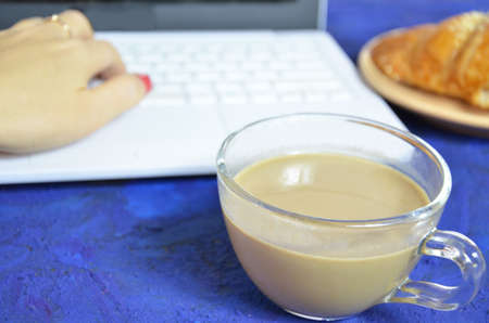 Light lunch in office. Coffee and croissant near keyboard and notebook on white background top view...