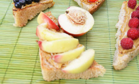 Composition different delicious toasts on green or pink crimson background. Healthy sandwich for breakfast or snack. Toast with raspberries, strawberries, banana and blueberries and peanut butter. picnicの写真素材