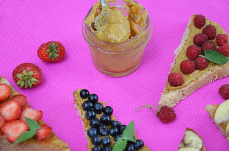 Composition different delicious toasts on green or pink crimson background. Healthy sandwich for breakfast or snack. Toast with raspberries, strawberries, banana and blueberries and peanut butter. picnicの写真素材
