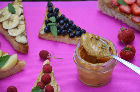 Composition different delicious toasts on green or pink crimson background. Healthy sandwich for breakfast or snack. Toast with raspberries, strawberries, banana and blueberries and peanut butter. picnicの写真素材