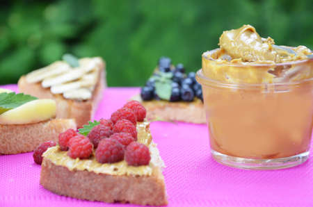 Composition different delicious toasts on green or pink crimson background. Healthy sandwich for breakfast or snack. Toast with raspberries, strawberries, banana and blueberries and peanut butter. picnicの写真素材