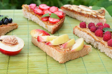 Composition different delicious toasts on green or pink crimson background. Healthy sandwich for breakfast or snack. Toast with raspberries, strawberries, banana and blueberries and peanut butter. picnicの写真素材