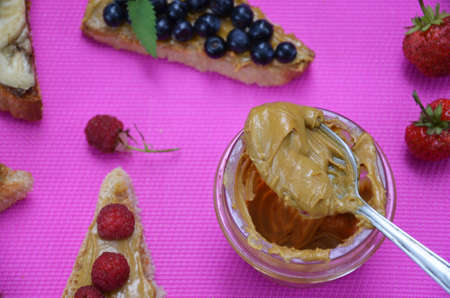 Composition different delicious toasts on green or pink crimson background. Healthy sandwich for breakfast or snack. Toast with raspberries, strawberries, banana and blueberries and peanut butter. picnicの写真素材