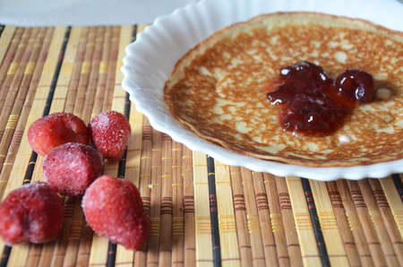 freshly fried homemade french crepes on a plate with strawberries, banana slices and fresh cream, horizontal view from above, close-upの写真素材