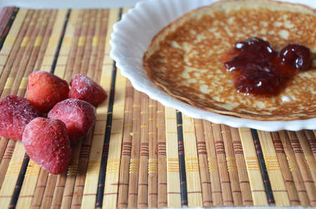 freshly fried homemade french crepes on a plate with strawberries, banana slices and fresh cream, horizontal view from above, close-upの写真素材