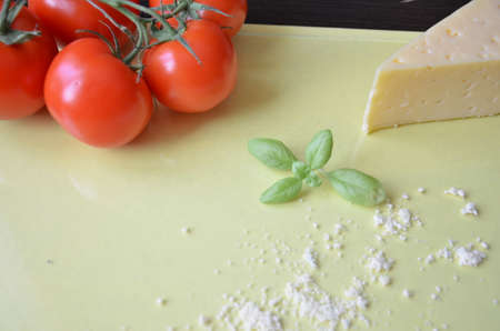Italian food background with tomatoes, basil, parmesan. Ingredients onellow table Copy space Top viewの写真素材