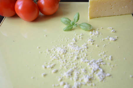 Italian food background with tomatoes, basil, parmesan. Ingredients onellow table Copy space Top viewの写真素材