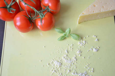 Italian food background with tomatoes, basil, parmesan. Ingredients onellow table Copy space Top viewの写真素材