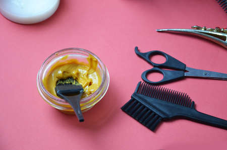 Barber shop set with hair dye, hairbrush, scissors, spray and brush on pink red background.