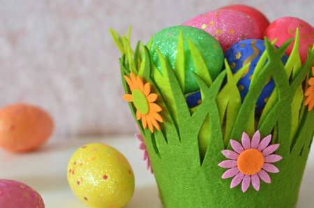 Happy Easter Day. Easter eggs concept. Closeup Colorful Easter eggs in nest and basket green gress on white wooden backgroundの写真素材