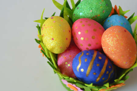 Happy Easter Day. Easter eggs concept. Closeup Colorful Easter eggs in nest and basket green gress on white wooden backgroundの写真素材