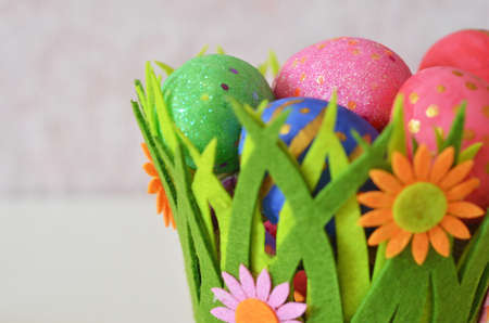 Happy Easter Day. Easter eggs concept. Closeup Colorful Easter eggs in nest and basket green gress on white wooden backgroundの写真素材
