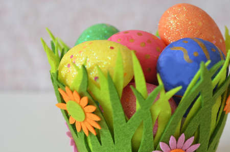 Happy Easter Day. Easter eggs concept. Closeup Colorful Easter eggs in nest and basket green gress on white wooden backgroundの写真素材
