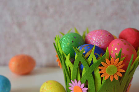 Happy Easter Day. Easter eggs concept. Closeup Colorful Easter eggs in nest and basket green gress on white wooden backgroundの写真素材