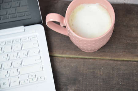 Computer image coffee cup resting on a wooden backgroud. desktop, work space of a journalist, blogger, freelancer, office supplies glasses pen, notebook.の写真素材