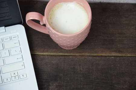 Computer image coffee cup resting on a wooden backgroud. desktop, work space of a journalist, blogger, freelancer, office supplies glasses pen, notebook.の写真素材