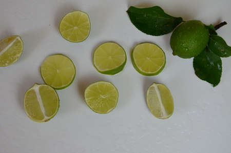 Flat lay of citrus fruits like lime and lemon with lemon tree leaves on light pink background making a frameの写真素材