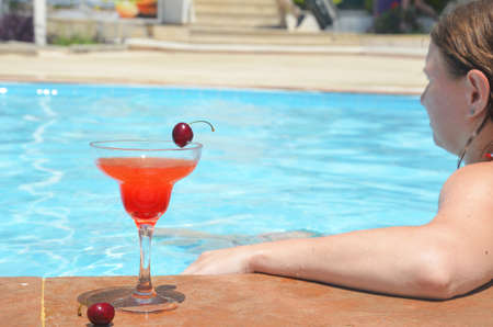 Tasty red cocktail background swimming pool. Margarita cocktail with a glass of cherries.の写真素材