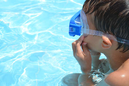 Teenager boy wearing mask swimming in the pool. Happy holiday concept. Cute happy little boy swimming and snorking in the sea ocean in crystal blue waterの写真素材