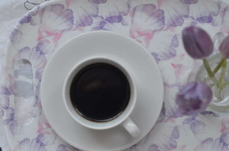 Tray with paper sketchbook, smartphone and spring flowers on pink bedding. Relaxing, or working, or writing diary or blog in bed at home.の写真素材