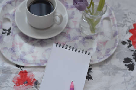 Tray with paper sketchbook, smartphone and spring flowers on pink bedding. Relaxing, or working, or writing diary or blog in bed at home.の写真素材