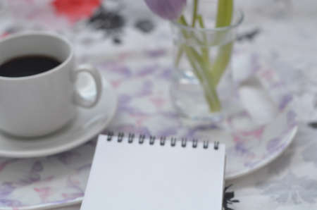 Tray with paper sketchbook, smartphone and spring flowers on pink bedding. Relaxing, or working, or writing diary or blog in bed at home.の写真素材
