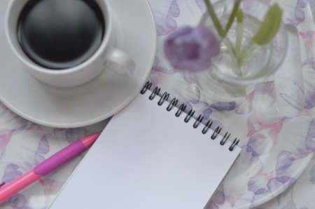Tray with paper sketchbook, smartphone and spring flowers on pink bedding. Relaxing, or working, or writing diary or blog in bed at home.の写真素材