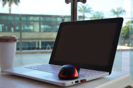 technology, business and modern life concept- close up of open laptop computer with mouse and coffee cup on table at hotel terrace balcony.の写真素材