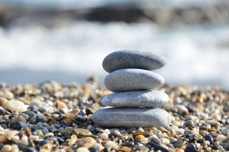 Zen pyramid of spa stones on the blurred sea background. Sand on a beach. Sea shores. Water waves texture. Place for text. concept of balance and spiritualityの写真素材