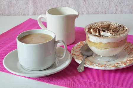 coffee with whipped cream and chocolate for breakfast. gourmet breakfast, coffee with milk, milk jug, tasty cake with whipped cream, sprinkled with chocolate or cinnamon on a raspberry backgroundの写真素材