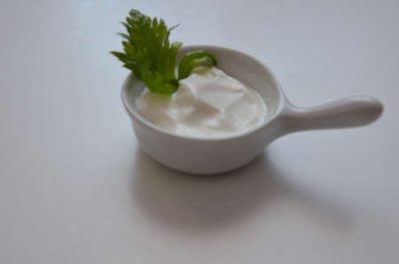 white sauce in a saucepan with greens, parsley, cilantro on a white background.の写真素材