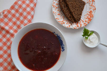 Traditional Ukrainian Russian borscht with white beans on the bowl. Plate of red beet root soup borsch on white background. Beetroot soup Top view. Traditional Ukraine food cuisine with bread.の写真素材