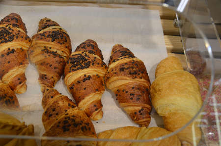 Delicious creamy croissant on paper in the window of the pastry shop, delicious pastries. Close-up of Croissants on shelf in bakery shop. Fresh baked croissant pastry on sale in cafeの写真素材