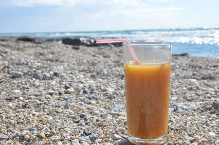 summer orange juice against the sea on the shore. concept of rest, travel, relax, ecologyの写真素材