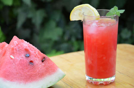 Colorful tropical fresh watermelon smoothie summer drinks in the glasses on wood table background. Refreshing watermelon coteil with slimon against the background of green foliage. The concept of leisure, travel.の写真素材