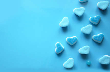 An assortment of colourful, festive sweets, blue marmalade in the shape of a heart on a blue background with a variety of caramels and candies, marshmallows. Abstract background. top view copy space.の写真素材