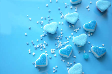 An assortment of colourful, festive sweets, blue marmalade in the shape of a heart on a blue background with a variety of caramels and candies, marshmallows. Abstract background. top view copy space.の写真素材