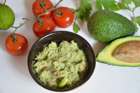 A delicious Bowl of Guacamole next to fresh ingredients on a table with tortilla chips and salsa. sandwich with guacamole, red hot pepper, lime, lemon, avocado.の写真素材