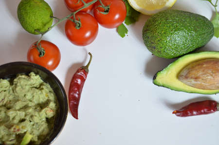 A delicious Bowl of Guacamole next to fresh ingredients on a table with tortilla chips and salsa. sandwich with guacamole, red hot pepper, lime, lemon, avocado.の写真素材