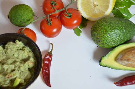 A delicious Bowl of Guacamole next to fresh ingredients on a table with tortilla chips and salsa. sandwich with guacamole, red hot pepper, lime, lemon, avocado.の写真素材