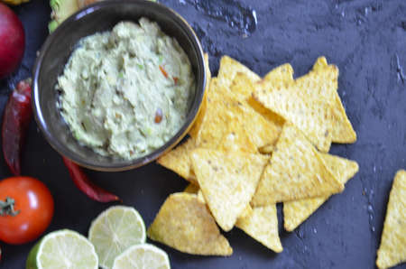 Mexican corn chips nachos with salsa dip on a black background with guacamole sauce, avacoda with lime and hot pepper tamato.の写真素材